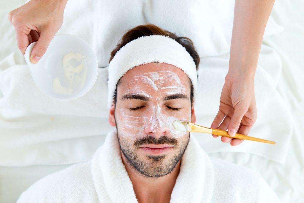Man laying down getting cream rubbed on his face