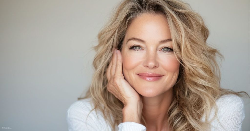 Smiling woman with glossy lips illustrating lip filler result (model).