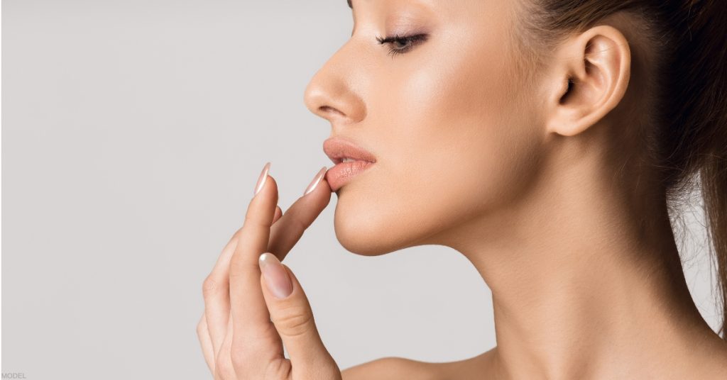 Smiling woman with glossy lips illustrating lip filler result (model).