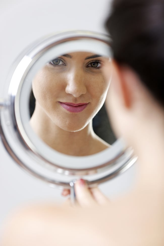 woman looking into mirror