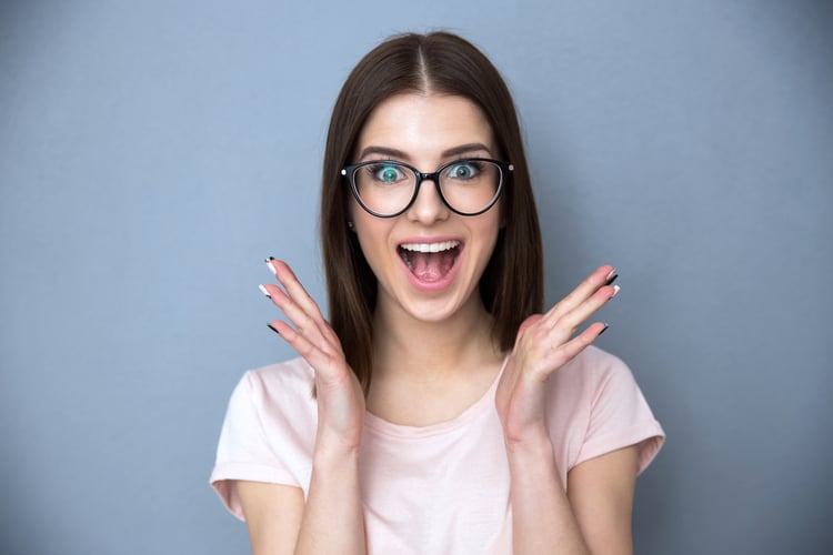 Surprised young woman in glasses over gray background-1